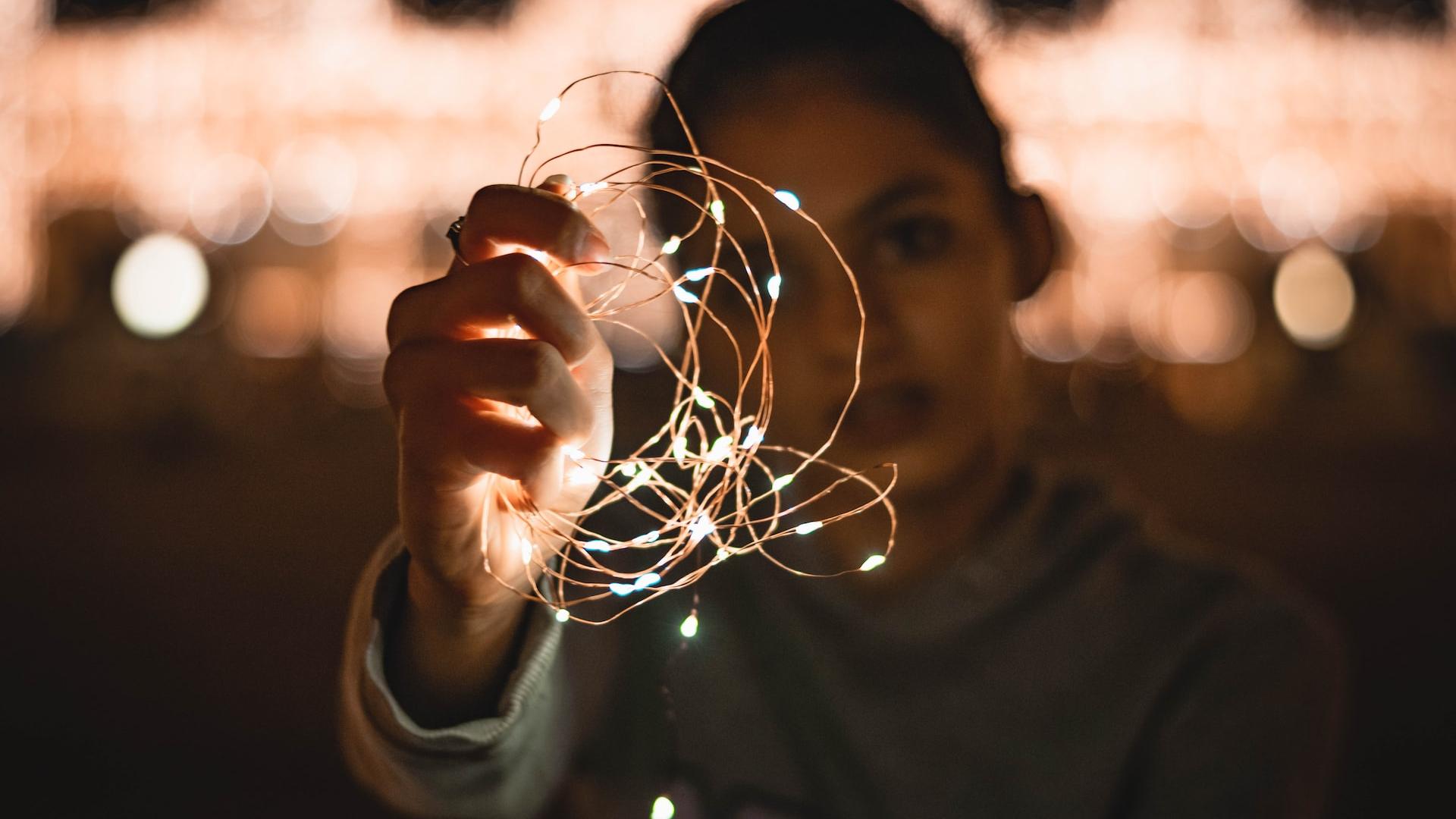 a woman holding a string of lights in her hand